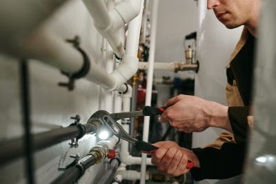 Technician inspecting commercial plumbing pipes in Saratoga